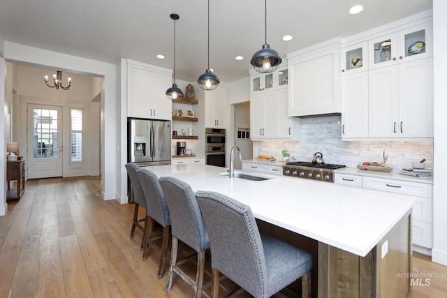 kitchen with open shelves, a sink, white cabinets, appliances with stainless steel finishes, and tasteful backsplash