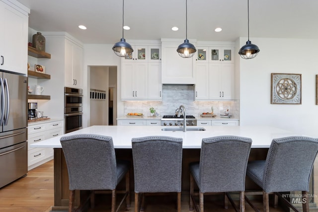 kitchen featuring open shelves, appliances with stainless steel finishes, light countertops, and a sink