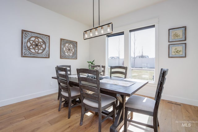 dining area with a wealth of natural light, visible vents, light wood finished floors, and baseboards