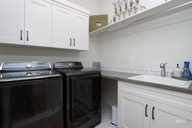 clothes washing area with washing machine and clothes dryer, cabinet space, and a sink