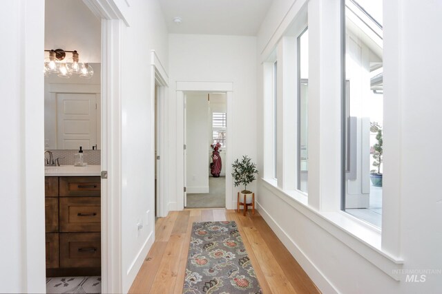 corridor with light wood-style flooring and baseboards