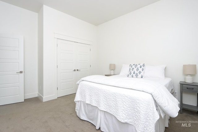 carpeted bedroom featuring baseboards and a closet