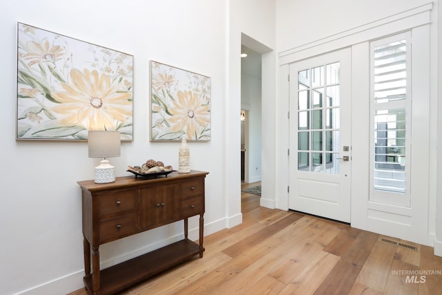 entrance foyer featuring a wealth of natural light, visible vents, baseboards, and wood finished floors