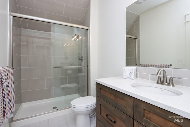 bathroom featuring toilet, a stall shower, and vanity