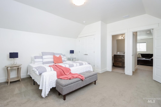 bedroom featuring baseboards, lofted ceiling, a closet, light colored carpet, and connected bathroom