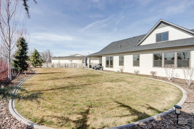 rear view of property with a yard, fence, and board and batten siding