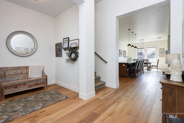 hall featuring stairway, baseboards, and light wood-type flooring