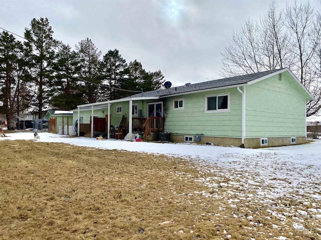 snow covered back of property with a lawn and cooling unit