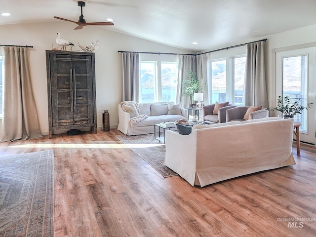 living room featuring ceiling fan, light hardwood / wood-style floors, and vaulted ceiling