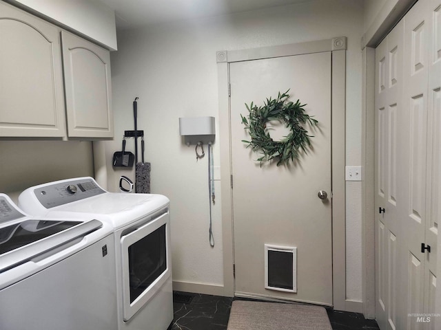 clothes washing area featuring cabinets and separate washer and dryer