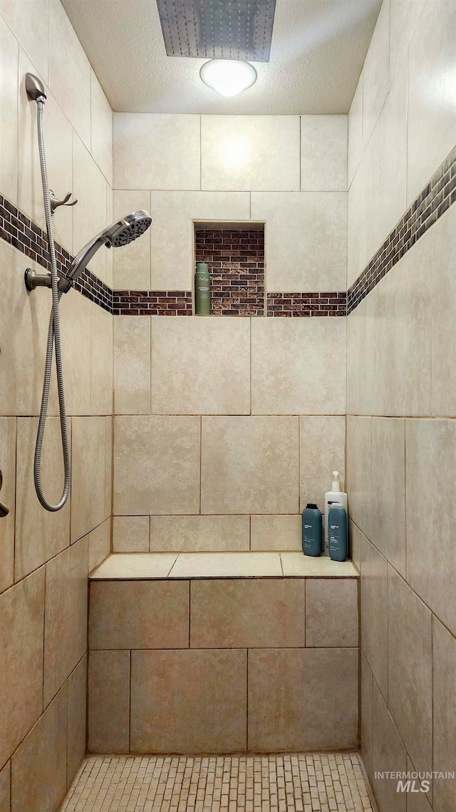 bathroom featuring a textured ceiling and tiled shower