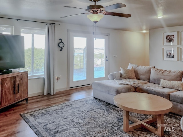 living room featuring ceiling fan, wood-type flooring, and a wealth of natural light