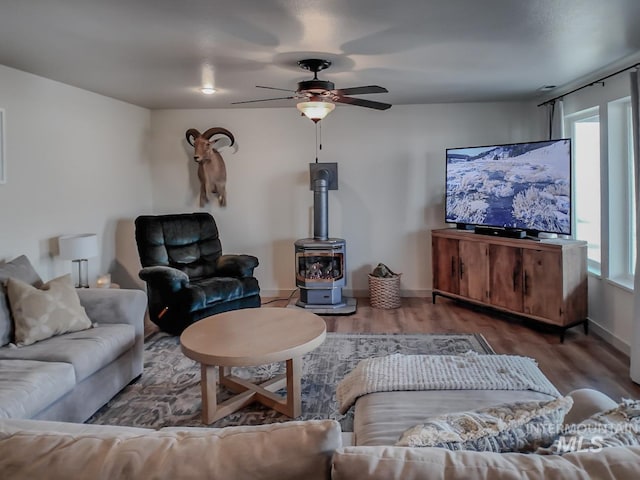 living room featuring a wood stove, ceiling fan, and dark hardwood / wood-style floors