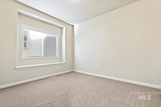 carpeted spare room with visible vents and baseboards