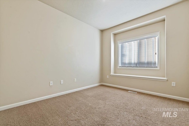 empty room with baseboards, visible vents, and carpet floors