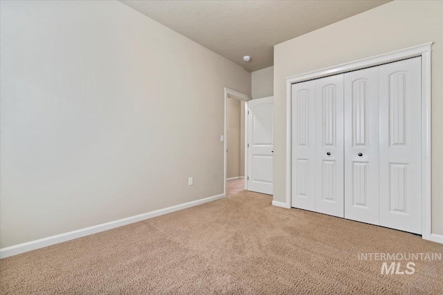 unfurnished bedroom featuring a closet, baseboards, carpet, and a textured ceiling