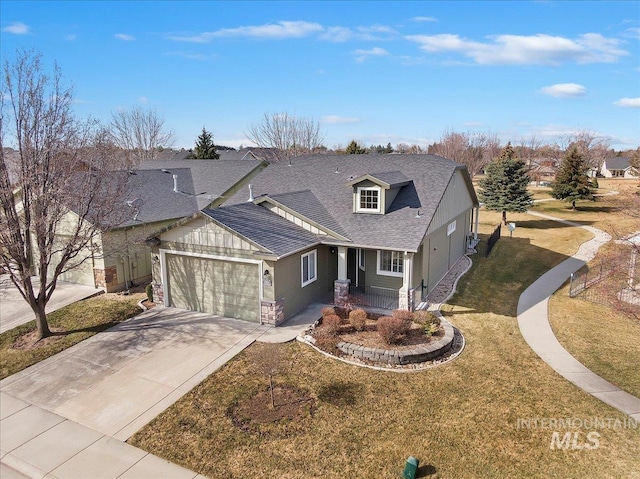 view of front of home with a front lawn, stone siding, roof with shingles, concrete driveway, and an attached garage