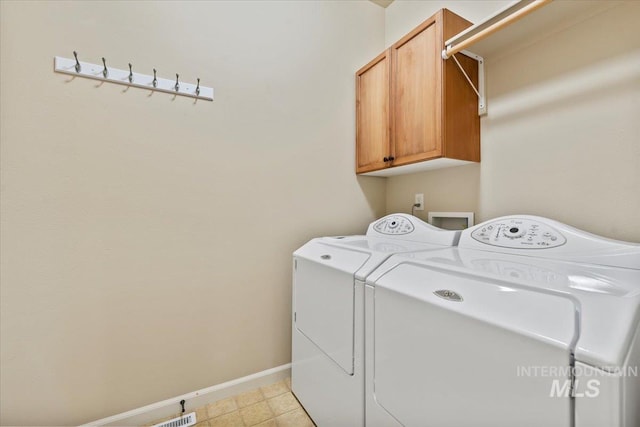 clothes washing area with washing machine and dryer, cabinet space, and baseboards