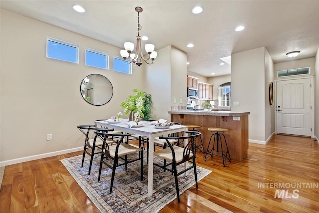 dining room with an inviting chandelier, recessed lighting, baseboards, and light wood-type flooring