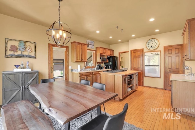 dining area with a chandelier, light wood-type flooring, and sink