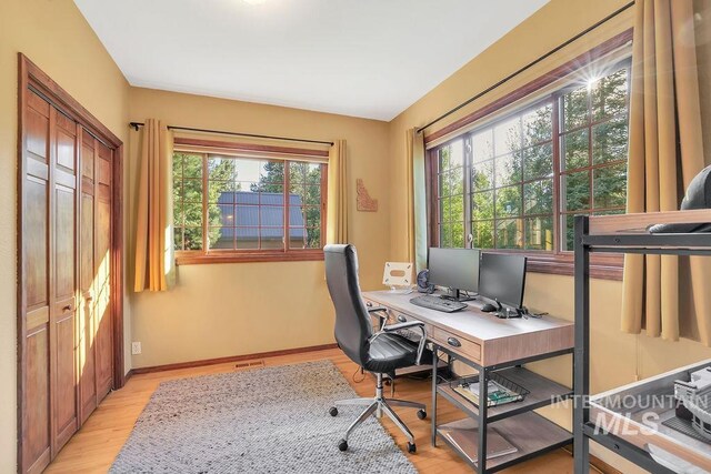 home office with light hardwood / wood-style flooring