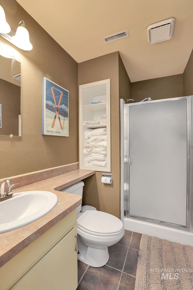 bathroom featuring tile patterned flooring, vanity, toilet, and a shower with shower door