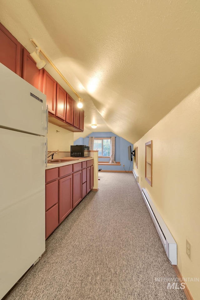 kitchen with light carpet, white refrigerator, vaulted ceiling, and baseboard heating