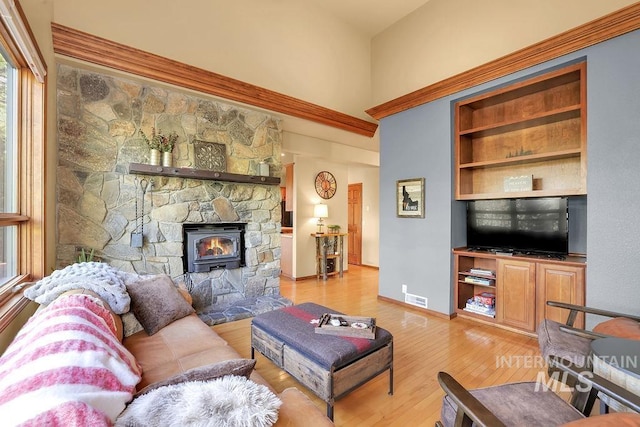 living room featuring built in features, a fireplace, and light hardwood / wood-style flooring