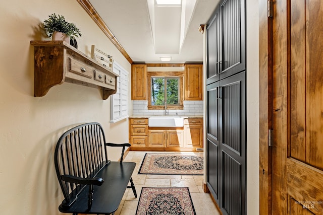 84 Jughandle Dr, Mccall, ID 83638 - kitchen featuring a sink, backsplash, light countertops, stone tile flooring, and brown cabinetry