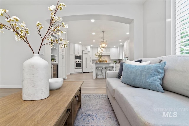 5446 E Branchwood Ct, Boise, ID 83716 - living area with light wood-style flooring, recessed lighting, a chandelier, wine cooler, and arched walkways