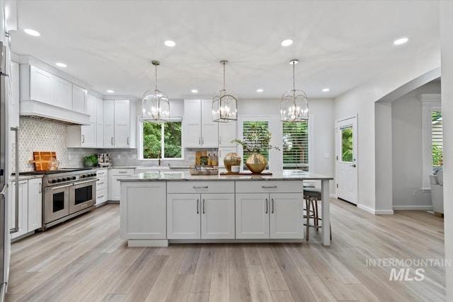 5446 E Branchwood Ct, Boise, ID 83716 - kitchen with double oven range, white cabinetry, a kitchen island, a chandelier, and tasteful backsplash
