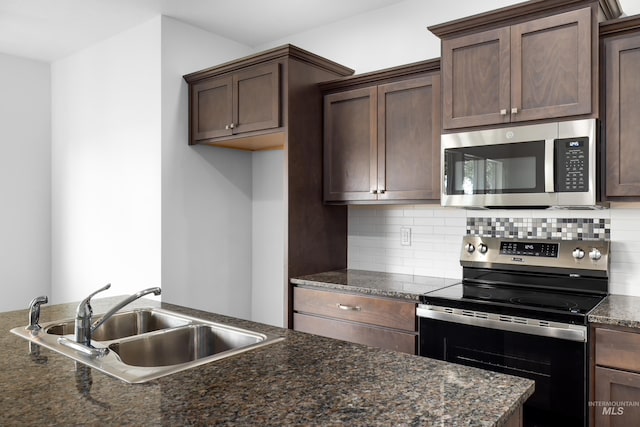 2928 W Los Flores Dr, Meridian, ID 83646 - kitchen with stainless steel appliances, a sink, decorative backsplash, dark brown cabinetry, and dark stone counters