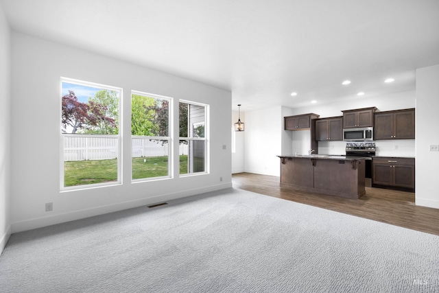 2928 W Los Flores Dr, Meridian, ID 83646 - kitchen featuring appliances with stainless steel finishes, baseboards, dark brown cabinetry, open floor plan, and recessed lighting