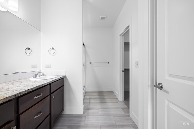 2928 W Los Flores Dr, Meridian, ID 83646 - bathroom featuring vanity, baseboards, a shower with door, and a spacious closet