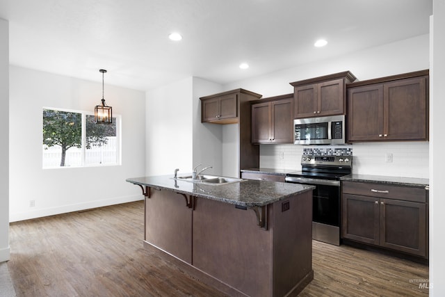 2928 W Los Flores Dr, Meridian, ID 83646 - kitchen with stainless steel appliances, a sink, backsplash, a kitchen bar, and dark wood-style floors