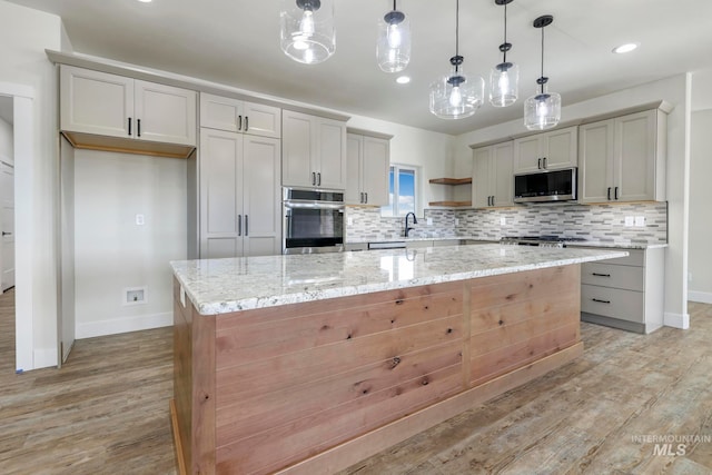 kitchen with open shelves, stainless steel appliances, backsplash, a kitchen island, and light wood-type flooring