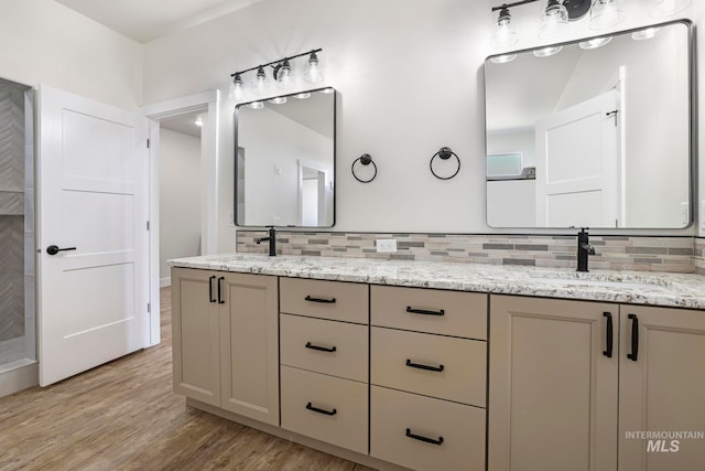 bathroom featuring double vanity, backsplash, a sink, and wood finished floors