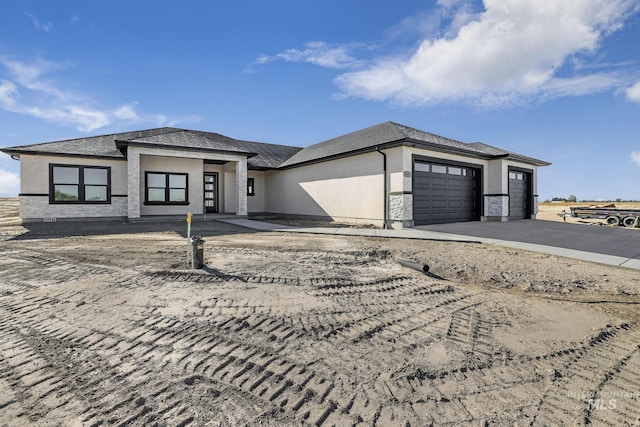 prairie-style house with driveway, an attached garage, and stucco siding