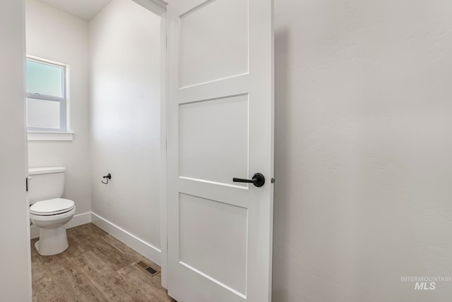 bathroom featuring baseboards, visible vents, toilet, and wood finished floors