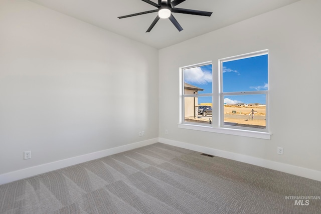 carpeted empty room with ceiling fan, visible vents, and baseboards