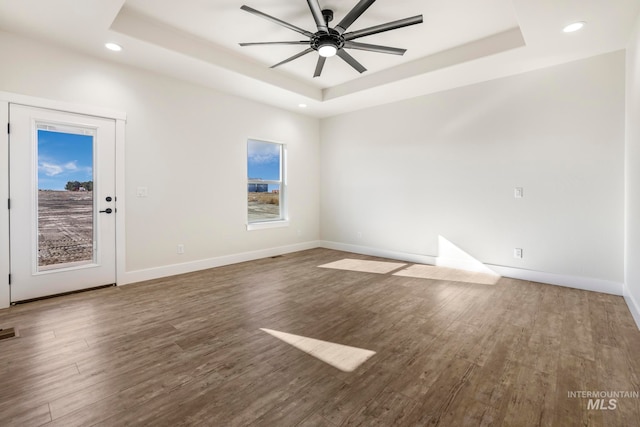 unfurnished room featuring ceiling fan, baseboards, a raised ceiling, and wood finished floors