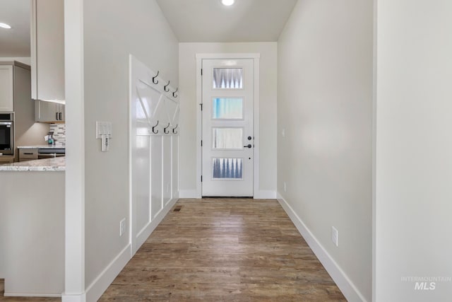 doorway featuring baseboards, wood finished floors, and recessed lighting