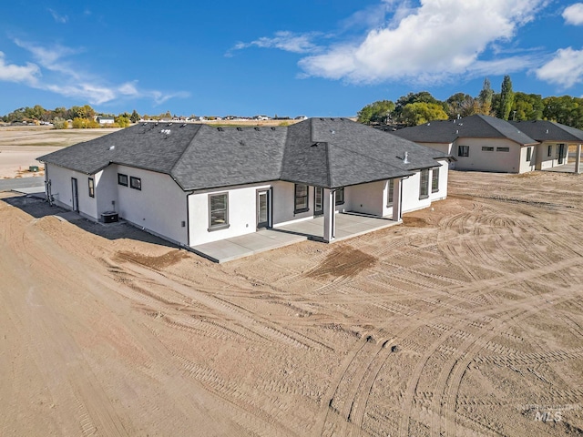 view of front of home featuring a patio area, roof with shingles, central AC, and stucco siding