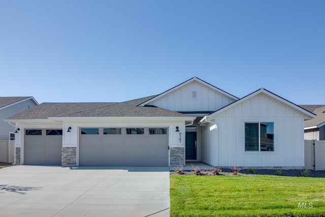 ranch-style home featuring board and batten siding, an attached garage, a front yard, and driveway