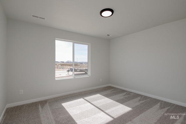 empty room featuring carpet floors, visible vents, and baseboards