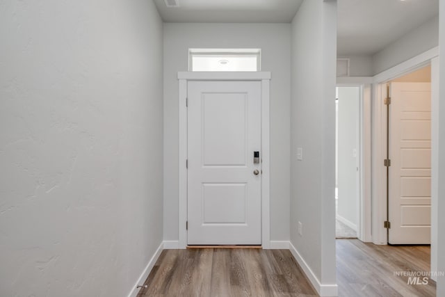 doorway to outside with baseboards and wood finished floors