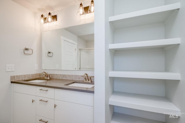 full bath with a shower with shower door, double vanity, and a sink