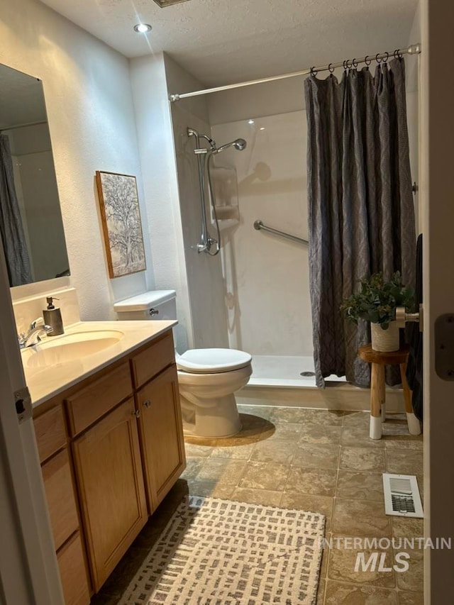 bathroom featuring a shower with shower curtain, vanity, toilet, and a textured ceiling