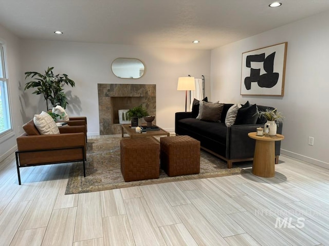 living room featuring a tiled fireplace and light wood-type flooring