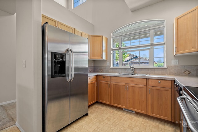 kitchen with stainless steel fridge with ice dispenser, a sink, healthy amount of natural light, light countertops, and a towering ceiling